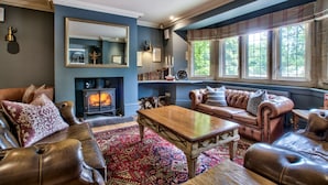A traditional living room with leather sofas, a wooden coffee table, a fireplace, and a large mirror. - The Vines (Bampton)