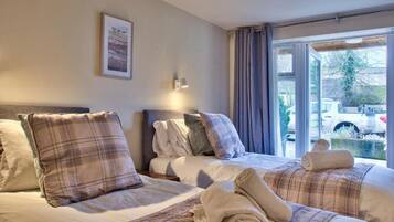 A hotel room with two beds, a window with curtains, a framed picture on the wall, and a view of the outside.