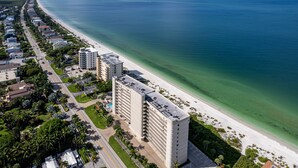 Eine Luftaufnahme eines Küstenhotels mit Strandzugang, mehrstöckigen Gebäuden und einer Straße, die parallel zum Strand verläuft.