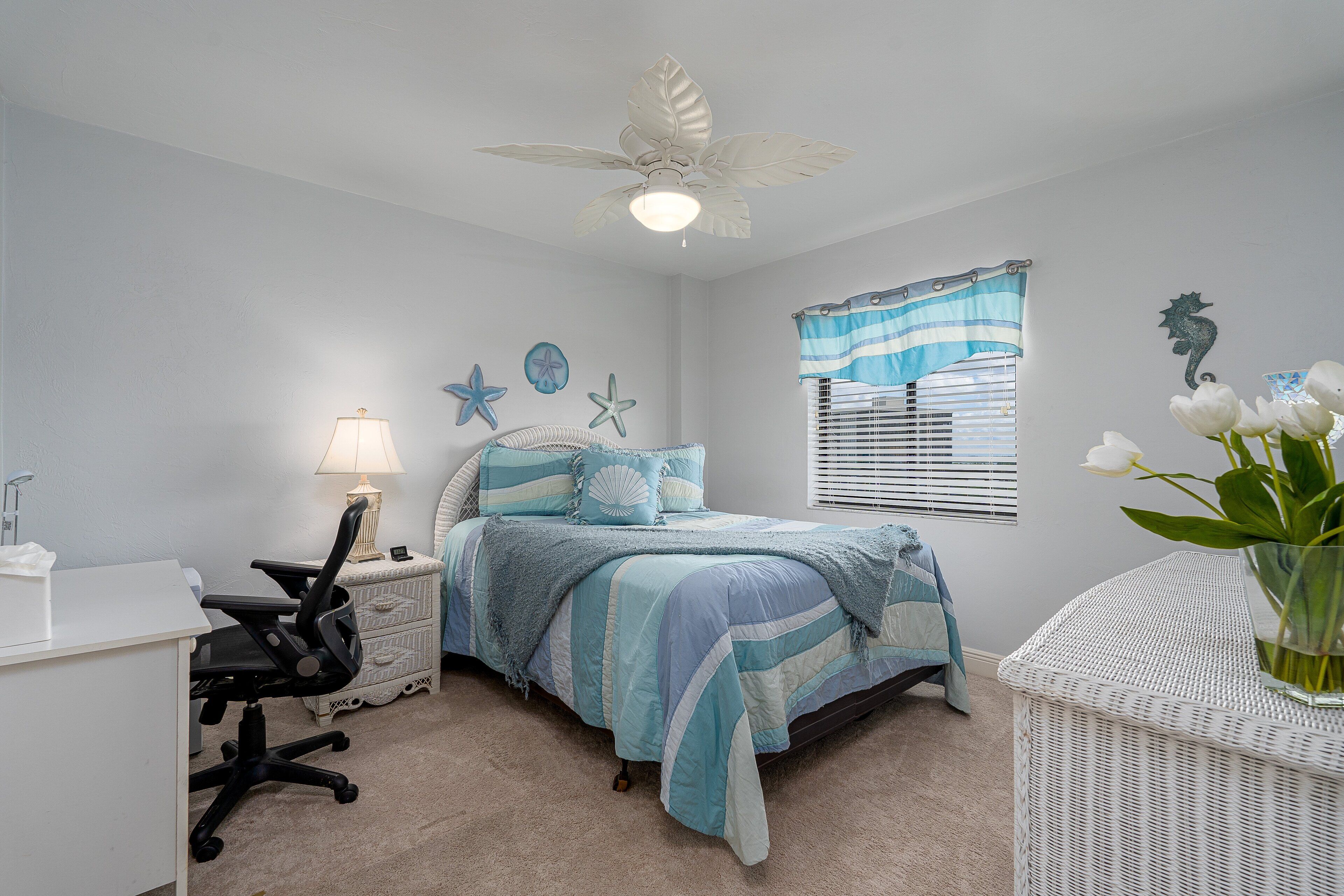 A bedroom with a bed, desk, chair, and a window with blinds.