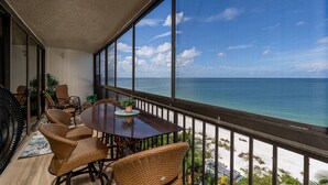 Ein Balkon mit Blick auf den Ozean, Korbmöbel und ein Esstisch.