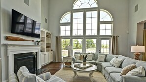 A spacious living room with a fireplace, a large TV, and a comfortable seating area with a sofa and chairs. - Beautiful Luxurious 4BD, 3.5 BA Home that sleeps 13 in the Bayside Golf & Resort Community! Amazing Pools, Fitness Centers, Tennis Courts, Walking trails, Freeman Stage with Music Performances! (Selbyville)