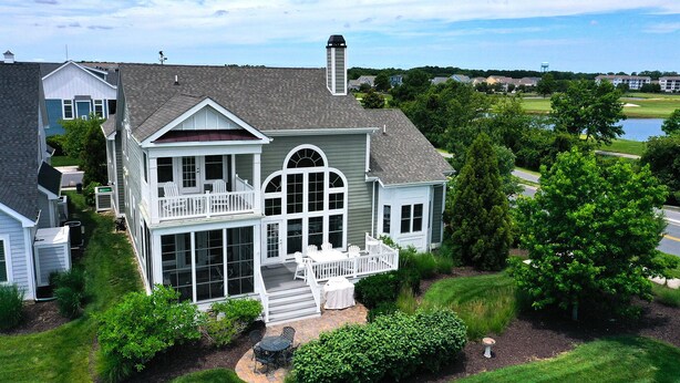 A large, two-story house with a balcony, a covered porch, and a view of a lake. - Beautiful Luxurious 4BD, 3.5 BA Home that sleeps 13 in the Bayside Golf & Resort Community! Amazing Pools, Fitness Centers, Tennis Courts, Walking trails, Freeman Stage with Music Performances! (Selbyville)