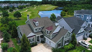 A large, two-story house with a garage, a driveway, and a pond in the background. - Beautiful Luxurious 4BD, 3.5 BA Home that sleeps 13 in the Bayside Golf & Resort Community! Amazing Pools, Fitness Centers, Tennis Courts, Walking trails, Freeman Stage with Music Performances! (Selbyville)