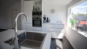 A modern kitchen with a stainless steel sink, built-in oven, and coffee maker.