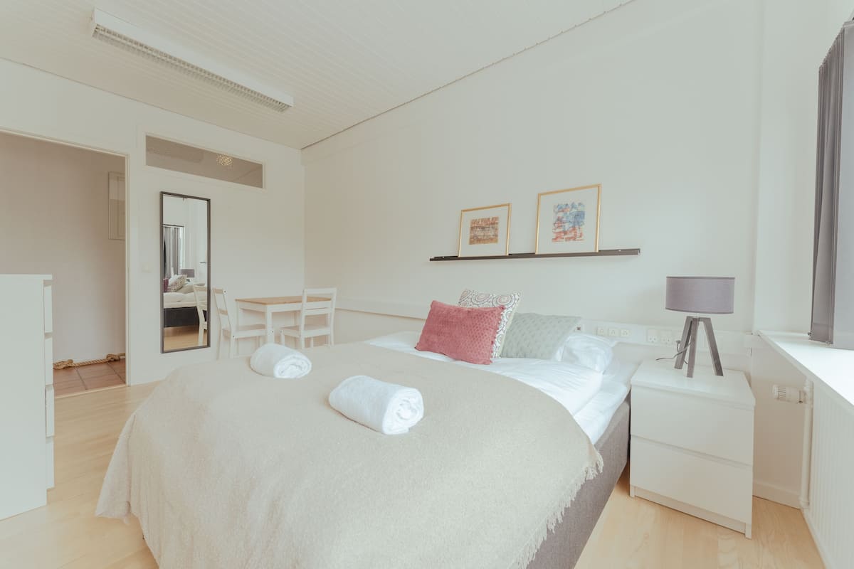 Ein modernes Schlafzimmer mit einem großen Bett, Nachttischen, einem Schreibtisch und einem Spiegel.