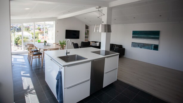 A modern kitchen with a central island, a dining area with chairs, and a view of the outdoors.