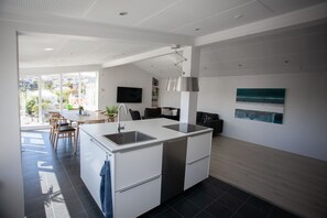 A modern kitchen with a central island, a dining area with chairs, and a view of the outdoors. - Luxury penthouse apartment - Tórshavn CT (Tórshavn)