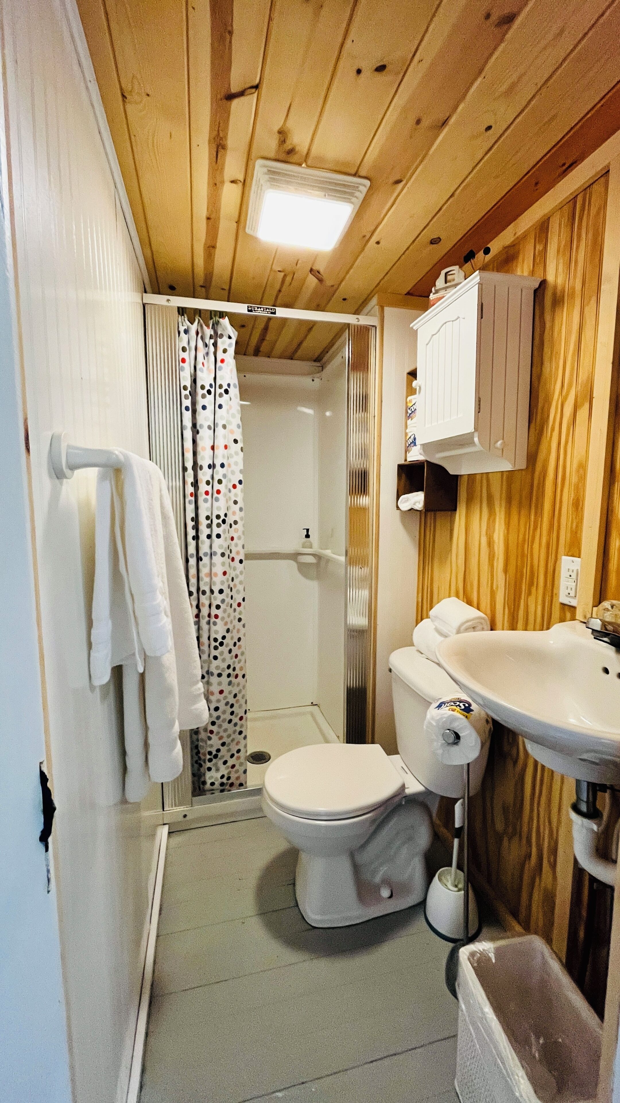 A compact bathroom with a shower, toilet, and sink.