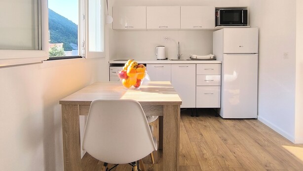 A modern kitchen with white cabinets, a microwave, and a refrigerator.