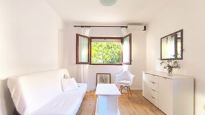 Een kamer met een bed, een bureau, een stoel, een kledingkast en een raam met uitzicht op groen.