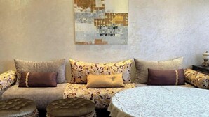 Un coin salon confortable avec un canapé, des poufs et une table ronde.