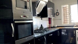 Une cuisine moderne avec des meubles de rangement noirs, un four à micro-ondes, une cuisinière et un ventilateur de plafond.