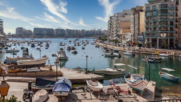 A marina with numerous boats docked, surrounded by residential buildings and a clear sky. - G Hotel by JL (St. Julian's)