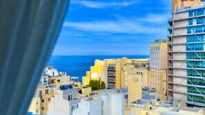 A cityscape with modern buildings, including a distinctive tall structure with yellow and blue accents. - G Hotel by JL (St. Julian's)