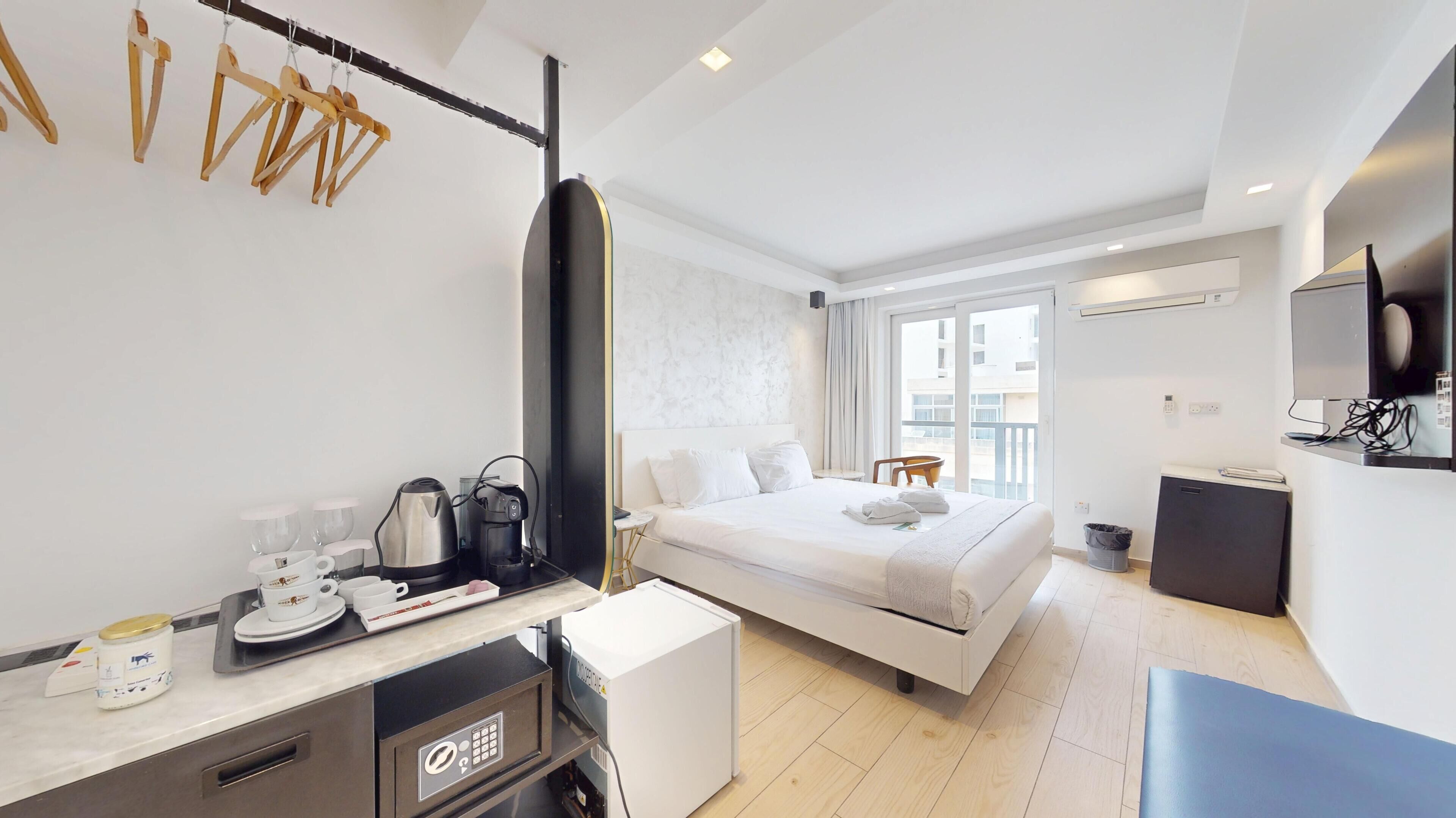 A hotel room with a bed, a desk with a coffee maker, a microwave, and a TV.
