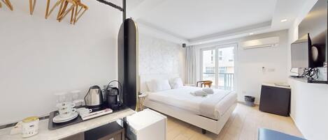 A hotel room with a bed, a desk with a coffee maker, a microwave, and a TV.