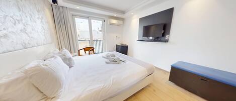 A hotel room with a bed, a TV mounted on the wall, and a view of the outside.