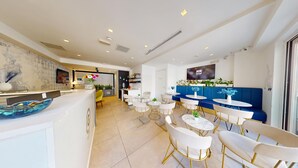 A modern hotel lobby with a reception desk, seating area, and a television screen. - G Hotel by JL (St. Julian's)