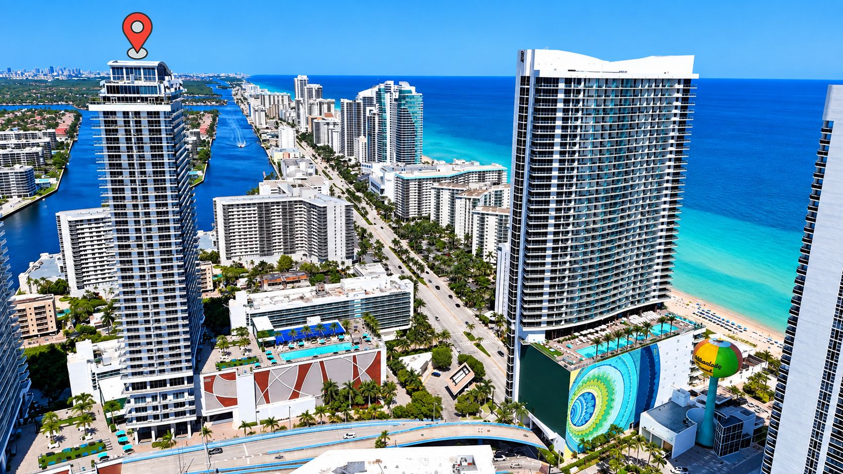 A high-rise hotel with a pool, beachfront view, and a marina.