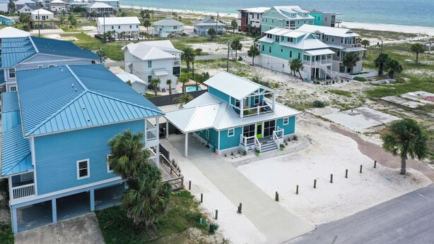 Una zona residenziale costiera con case dagli esterni blu e bianchi, una spiaggia e una vista libera sull'oceano.