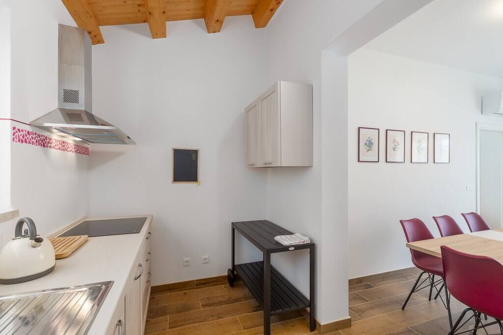 A compact kitchen with a stove, sink, and a small table.