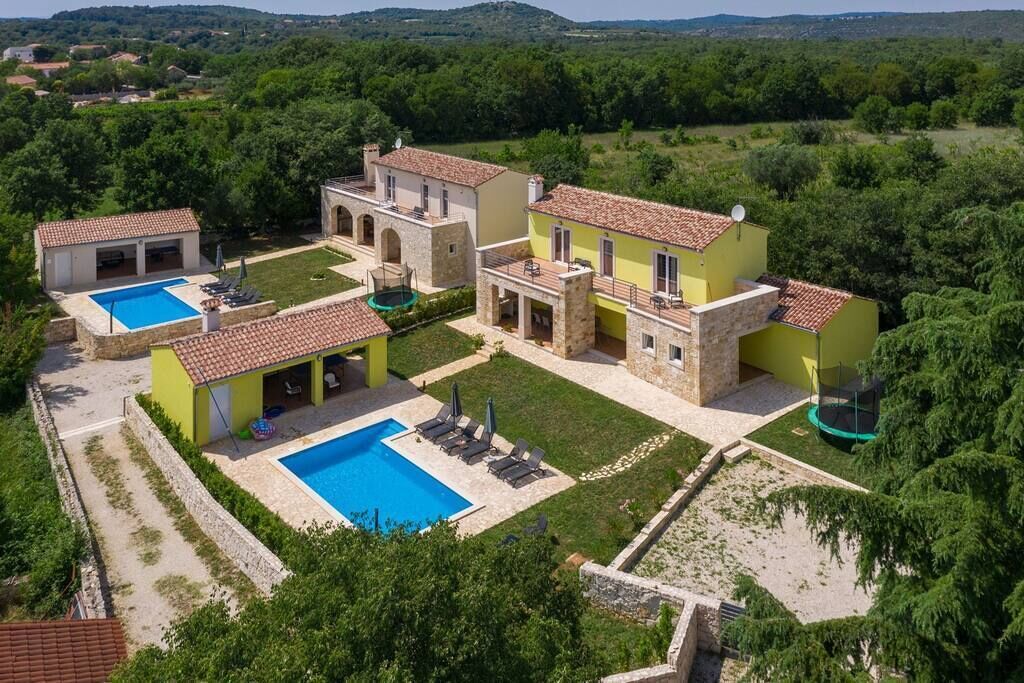 A villa with two swimming pools, a tennis court, and a trampoline.