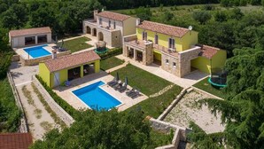 A villa with two swimming pools, a tennis court, and a trampoline.