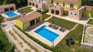 A villa with a swimming pool, outdoor seating, and a garden.