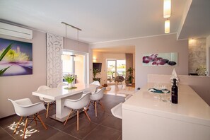 A modern kitchen with white cabinetry, a dining area with white chairs, and a bar area with a wine bottle. - Villa Anita with private pool, gym, 6 bedrooms, sea view (Kucine)