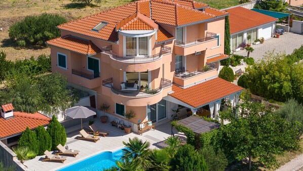 Una casa a più piani con piscina, balconi e giardino.
