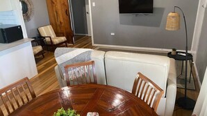 A dining area with a wooden table, chairs, and a white sofa. - Modern and Stylish 3Bed 2Bath home Townsville (Gulliver)