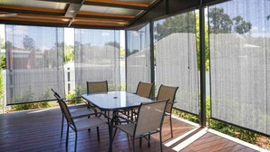 A covered patio with a glass table and chairs, surrounded by a mesh screen. - Modern and Stylish 3Bed 2Bath home Townsville (Gulliver)