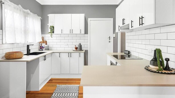 A modern kitchen with white cabinets, a black faucet, and a small island with a sink. - Modern and Stylish 3Bed 2Bath home Townsville (Gulliver)