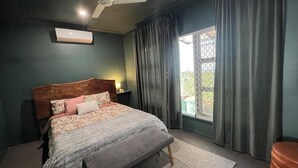 A bedroom with a bed, a ceiling fan, a window with curtains, and a nightstand. - Modern and Stylish 3Bed 2Bath home Townsville (Gulliver)