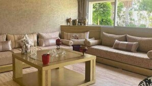 Un salon spacieux avec un grand canapé, une table basse et une vue sur la verdure environnante.