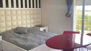 Une chambre à coucher moderne avec un grand lit, une table de chevet, un fauteuil rouge et un lustre.