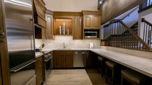 A modern kitchen with wooden cabinets, stainless steel appliances, and a marble countertop.
