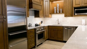 A modern kitchen with stainless steel appliances, wooden cabinets, and a marble countertop.