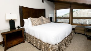 A large bed with a wooden headboard, two bedside lamps, a bedside table with a lamp, and a view of a mountainous landscape through the window. - Stein Eriksen Two Bedroom Loft 2 Apartment Hotel by RedAwning (Park City)