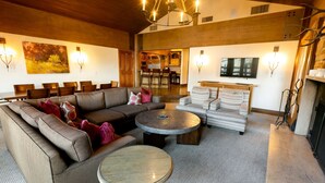 A spacious living room with a large sectional sofa, a round coffee table, and a patterned armchair. There is a fireplace and a television mounted on the wall. - Stein Eriksen Two Bedroom Loft 2 Apartment Hotel by RedAwning (Park City)