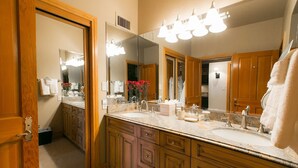 A bathroom with a double sink, wooden cabinets, a large mirror, and a towel rack. - Deluxe King Room With Hot Tub Hotel Room by RedAwning (Park City)