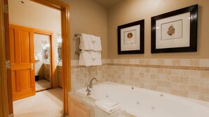 A bathroom with a bathtub, two framed leaf artworks, and a wooden door leading to another room. - Deluxe King Room With Hot Tub Hotel Room by RedAwning (Park City)