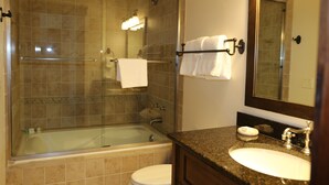 A bathroom with a glass-enclosed shower, a bathtub, a toilet, and a sink with a mirror above it.