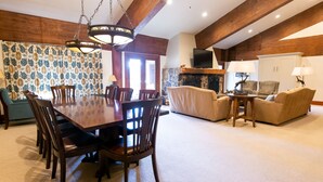 A spacious living room with a wooden dining table, chairs, and a fireplace. - Luxury Four Bedroom Multi-Level Townhouse 4 Townhouse by RedAwning (Park City)