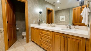 Un baño con armarios de madera, un lavabo doble y un espejo grande.