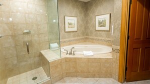 Un baño con ducha de vidrio, bañera independiente y dos cuadros en la pared.