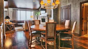 A spacious dining area with a round wooden table, upholstered chairs, and a hanging chandelier.