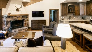 A living room with a stone fireplace, a television, a sofa, and a coffee table. - Luxury One Bedroom with Mountain View 1 Apartment Hotel by RedAwning (Park City)