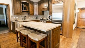 A kitchen with wooden cabinets, a marble countertop, and a stainless steel refrigerator. - Luxury One Bedroom with Mountain View 1 Apartment Hotel by RedAwning (Park City)